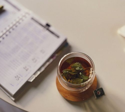 Person calmly drinking tea at a desk, signifying a daily routine.