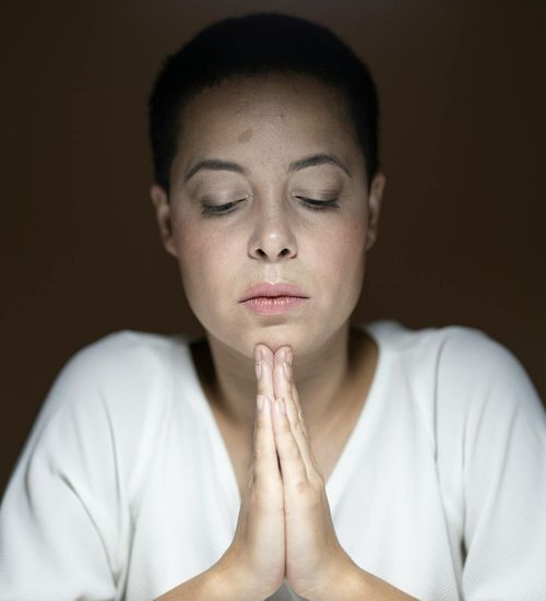 Woman with closed eyes meditating in a calm dark environment.